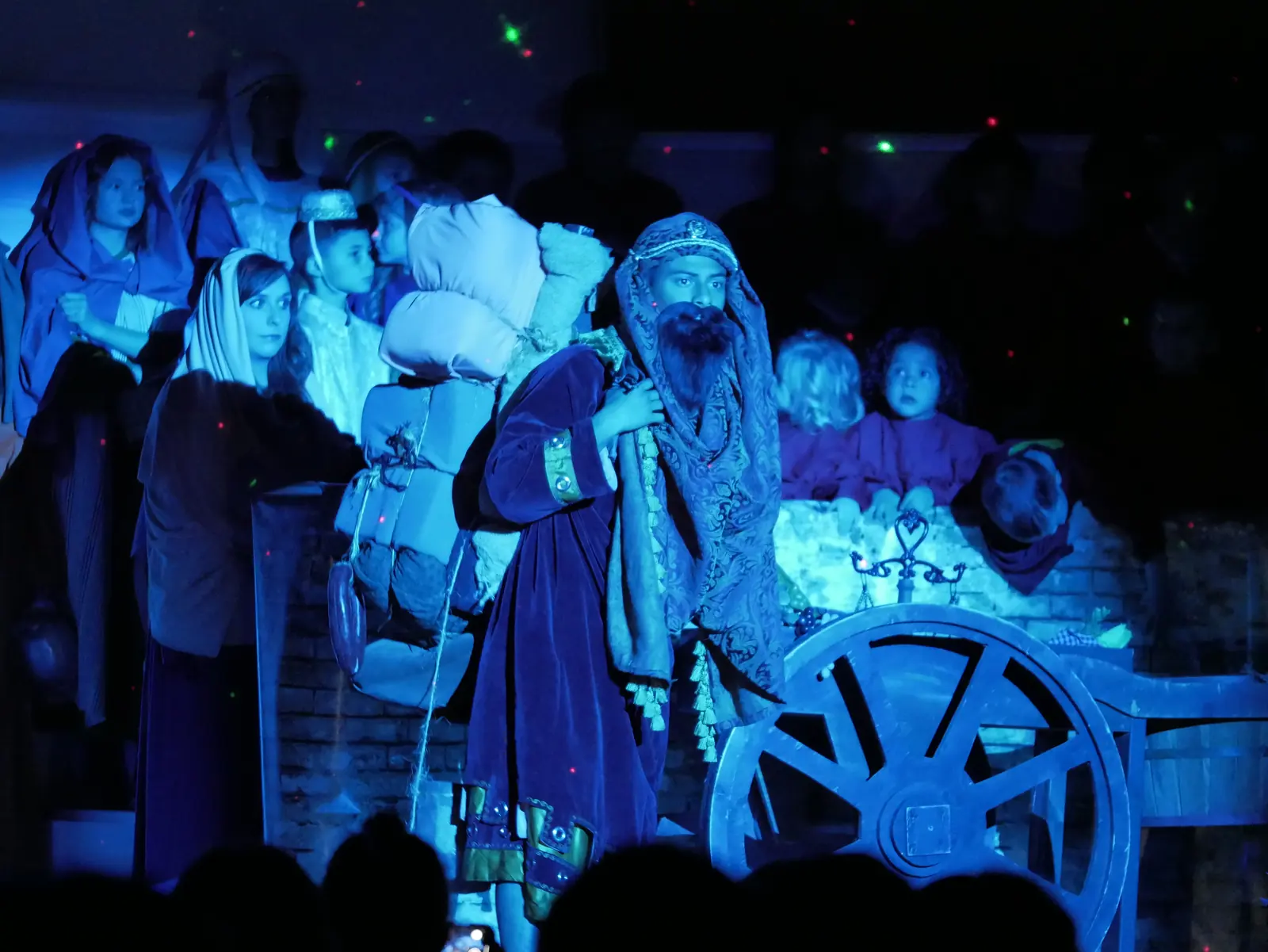 A bearded traveler with a heavy pack walking through the crowd in blue light